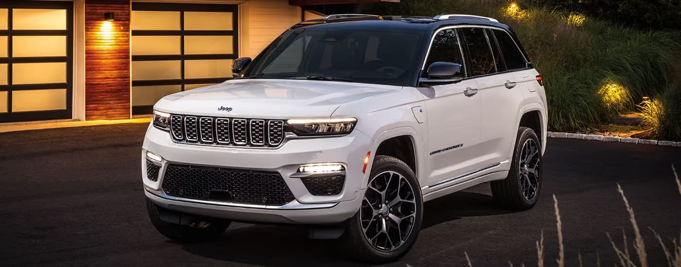 A white 2024 Jeep Grand Cherokee is shown parked in a driveway.