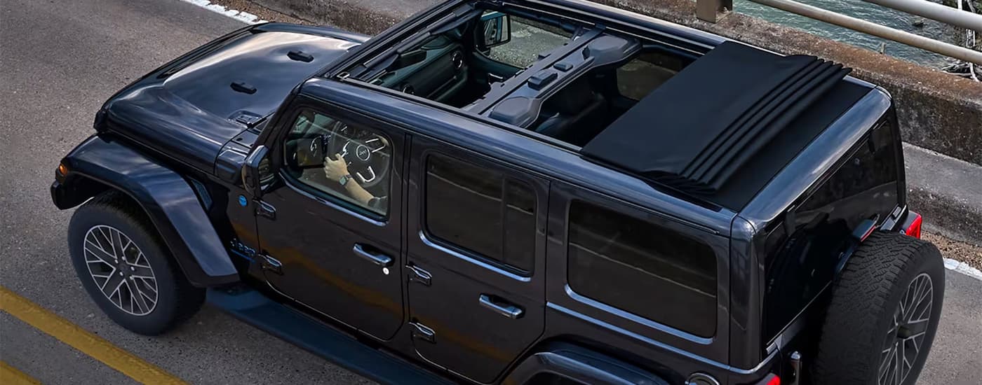 A black 2023 Jeep Wrangler is shown from above with the top down after visiting a Jeep dealer.