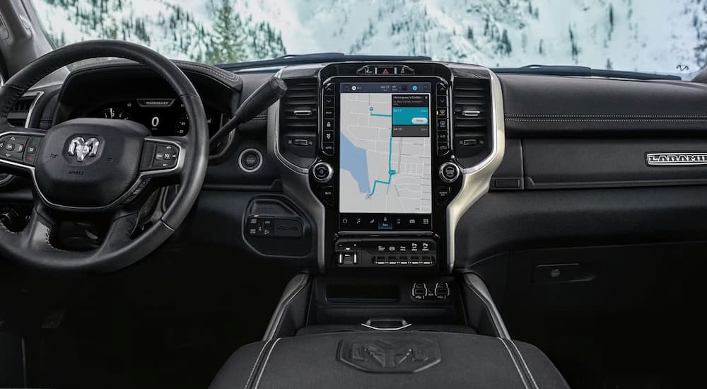 The steering wheel and infotainment center in a 2024 Ram 2500 Laramie at a Ram dealer.