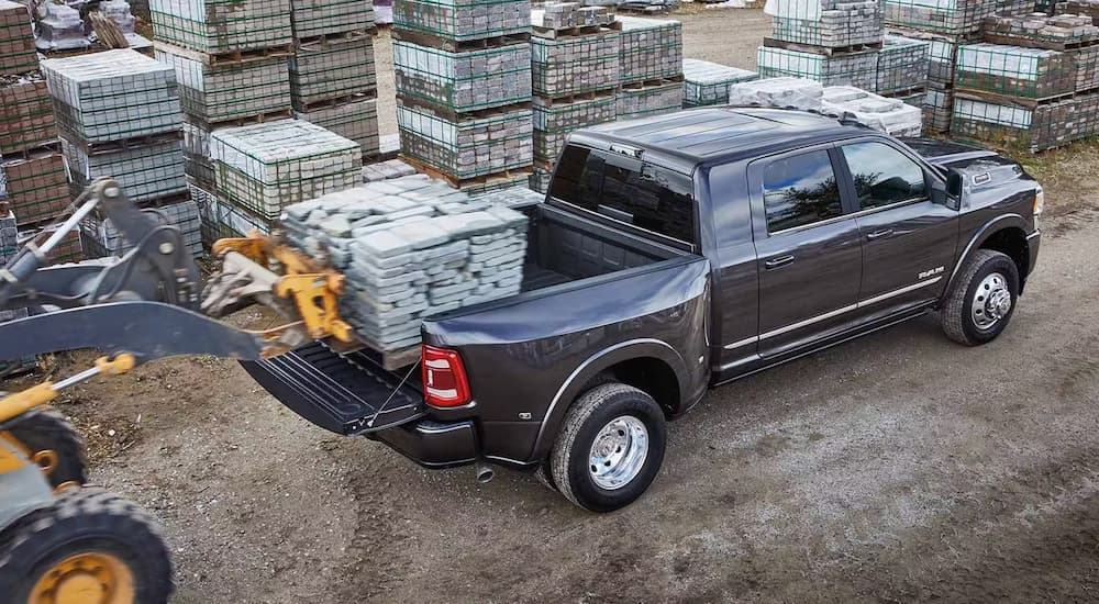 Overhead view of a tractor lowering a pallet of stone into the bed of a grey 2024 Ram 3500. 