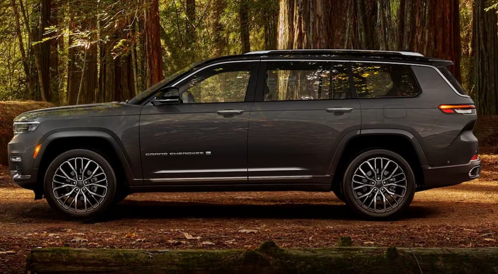 Side view of a grey 2024 Jeep Grand Cherokee L parked in the woods.