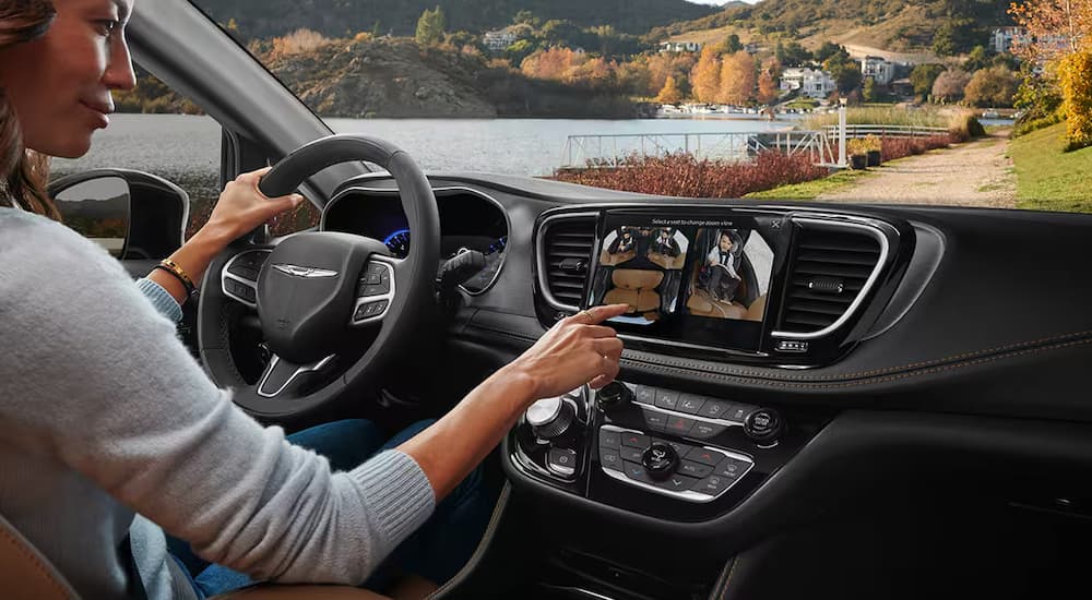 The driver of a 2024 Chrysler Pacifica using the interior FAMcam to monitor children in the back seats.