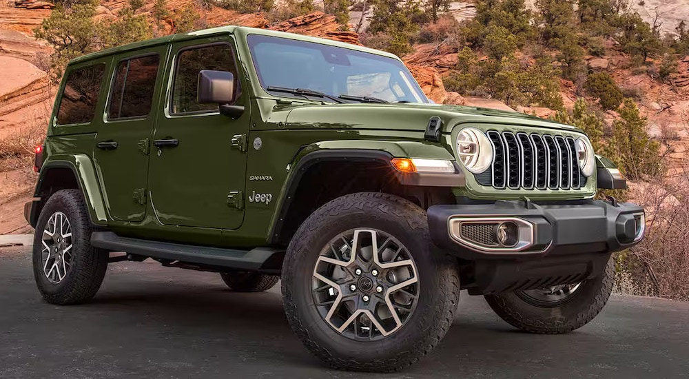 A green 2023 Jeep Wrangler Unlimited Sahara parked after leaving a used car dealership.