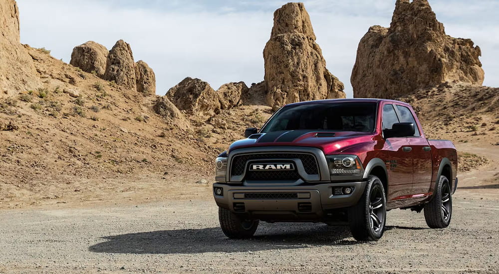 A red 2025 Ram 1500 Classic Warlock parked off-road and angled left.