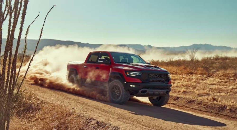 Red used 2022 Ram 1500 TRX for sale driving on a dirt road.