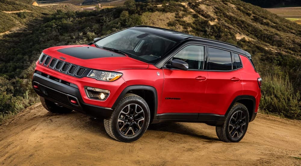 A red 2021 Jeep Compass Trailhawk parked off-road.
