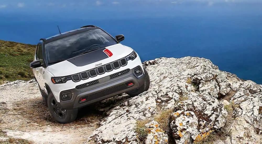 A white 2023 Jeep Compass Trailhawk parked off-road.
