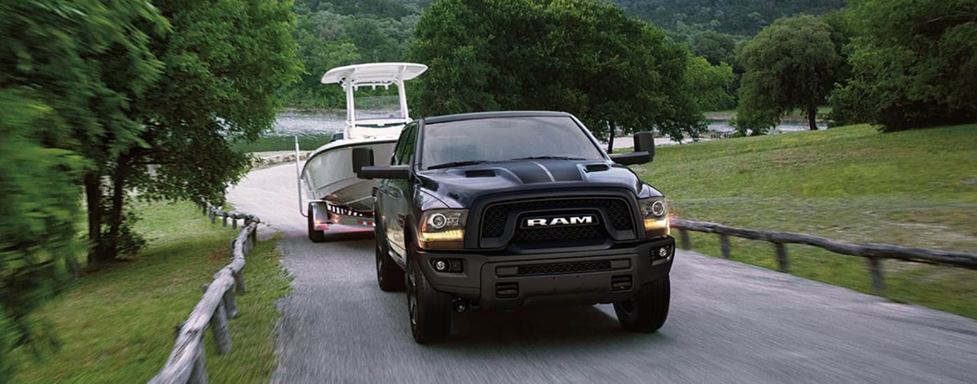 A grey 2019 Ram 1500 Classic towing a white boat from a lake.