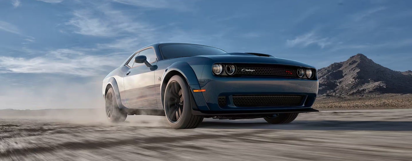 A blue 2023 Dodge Challenger Scat Pack driving on a dirt road.