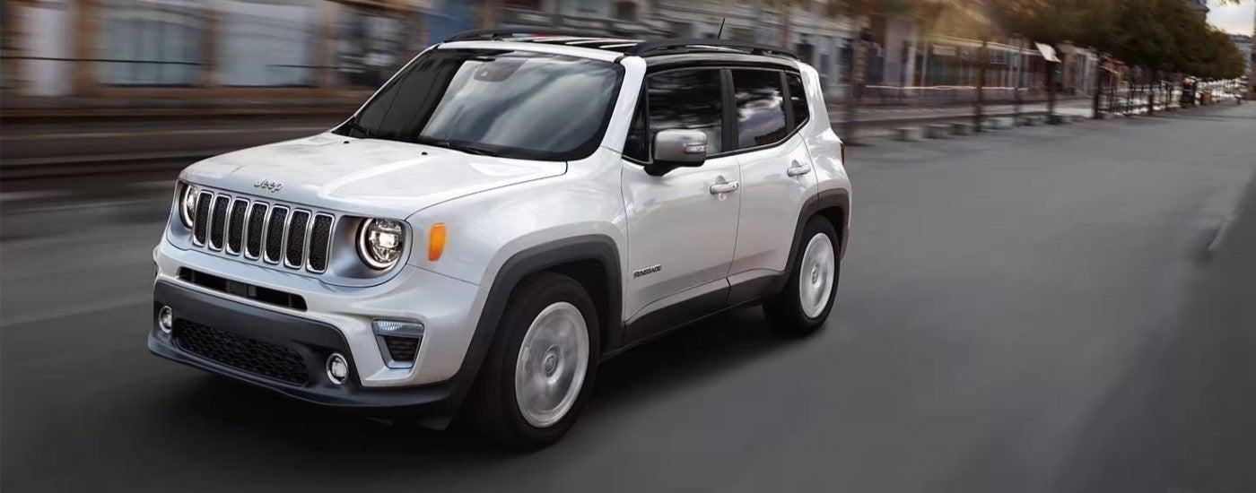 A white 2020 Jeep Renegade driving in a city.